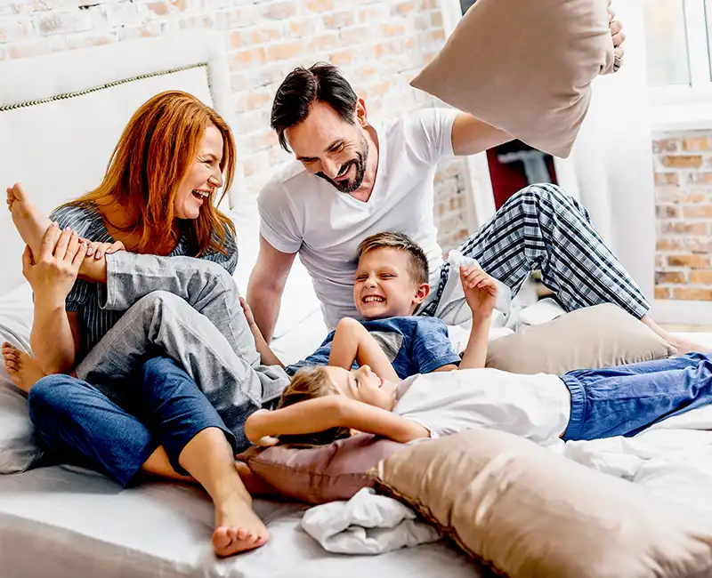 Parents and kids playing on a bed